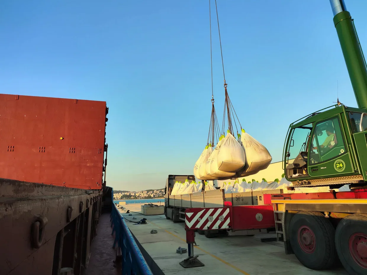 Big bags of cement lifted by a crane at a port